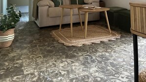 A living room with a beige sofa, a small wooden table, a patterned rug, a potted plant, and a painting on the wall. - Exclusive three-bedroom home just a few minutes from the beach. (El Puerto de Santa María)