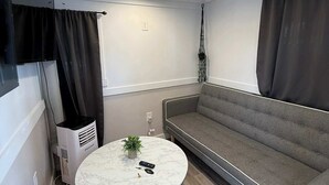A modern living room with a grey sofa, a round marble coffee table, and a TV mounted on the wall.