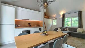 Une cuisine moderne avec des meubles blancs, une table à manger en bois et une cuisinière encastrée.