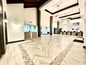 A spacious lobby with a herringbone patterned floor, large pillars, and a reception desk. - Shores of Panama 231 - Beautiful 3 Bedroom (Sleeps 8).  Same Floor Parking! No Elevators Needed (Panama City Beach)