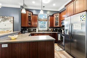 Eine Küche mit Holzausstattung, einem Edelstahlkühlschrank und Pendelleuchten.