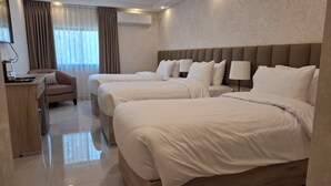 Habitación de hotel con dos camas, un escritorio, una silla, una lámpara y un equipo de aire acondicionado.