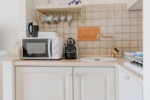 A kitchen with a microwave, coffee maker, and a tea box on the counter. - CASA GIULIA - Centro - Sanremo (Sanremo)