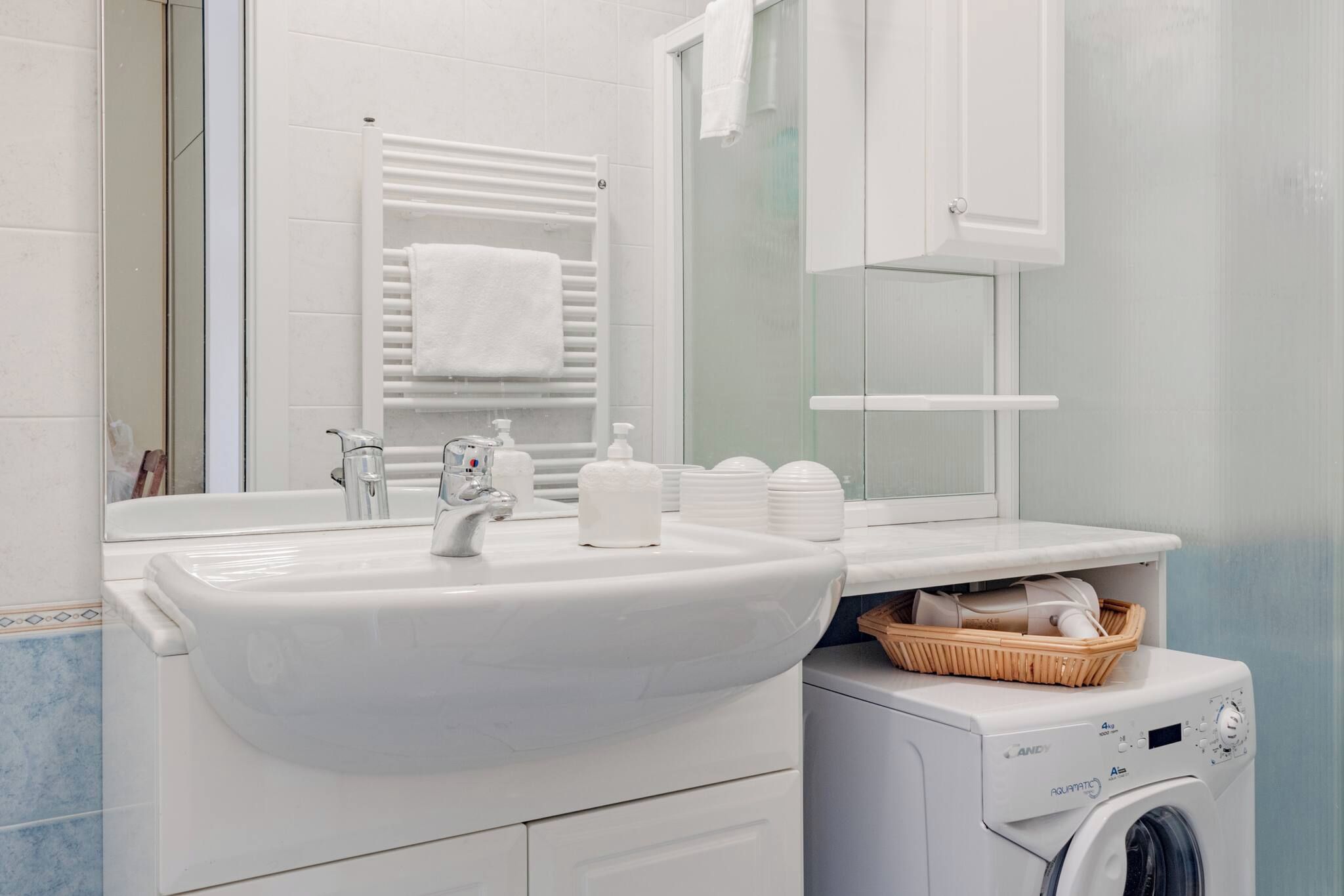 Une salle de bain avec un lavabo blanc, un miroir et un lave-linge.