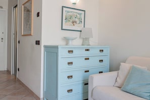 A room with a light blue chest of drawers, a white sofa with blue cushions, and a framed picture on the wall. - CASA GIULIA - Centro - Sanremo (Sanremo)