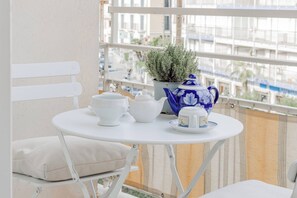 A balcony with a white table, a white chair, a potted plant, a white teapot, and a blue and white teacup set. - CASA GIULIA - Centro - Sanremo (Sanremo)