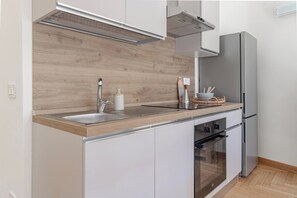 A modern kitchen with a stainless steel refrigerator, a built-in oven, and a wooden backsplash. - CASA MIMOSA - Parcheggio (Sanremo)
