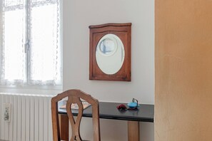 A room with a wooden chair, a table, a wall-mounted mirror, and a radiator. - CA' IN TE L'AIA - Taggia Centro (Taggia)