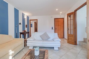 Una sala de estar con un sofá, una mesa de centro con una planta, una lámpara y una puerta.