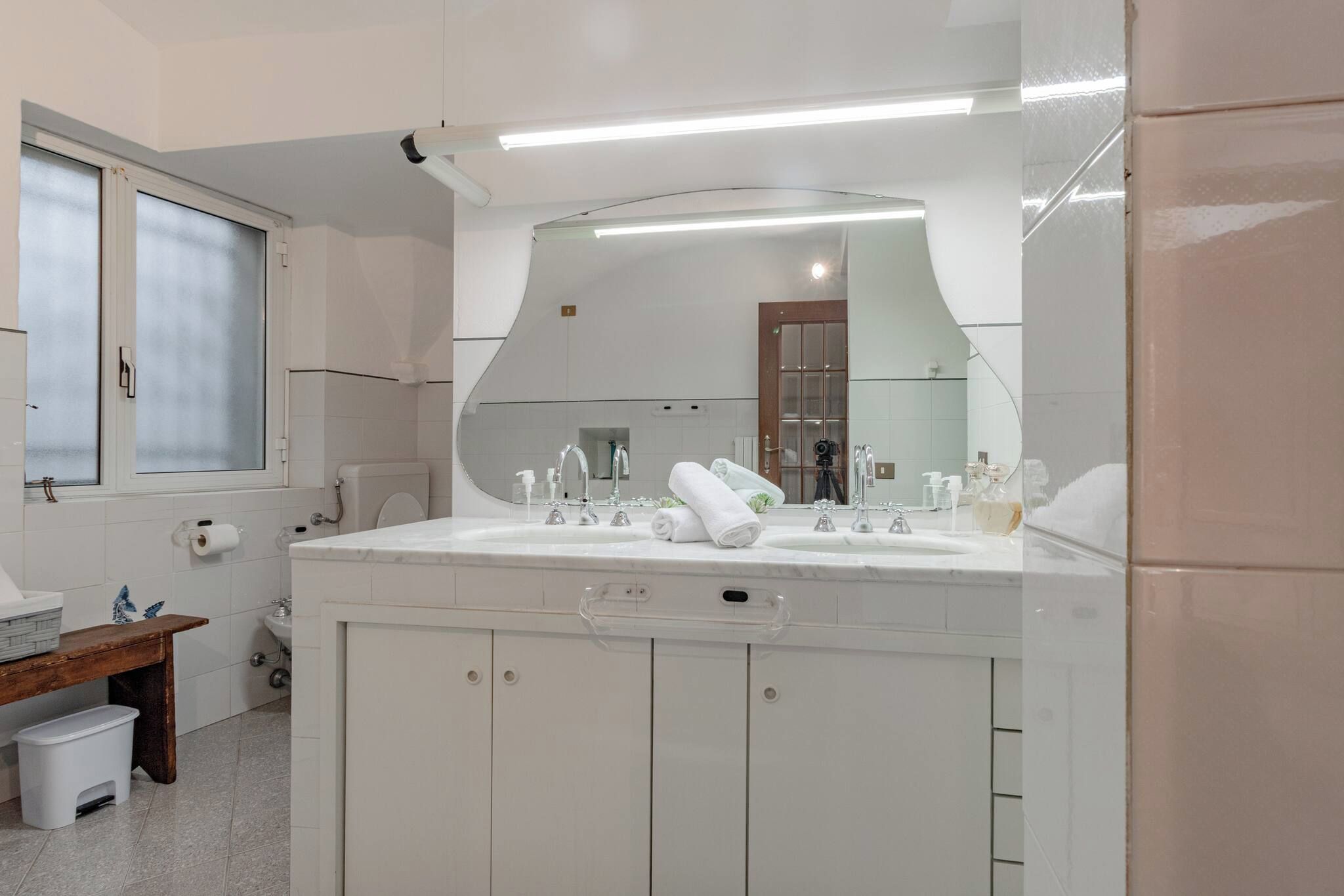 A modern bathroom with a large mirror, two sinks, and a vanity cabinet.