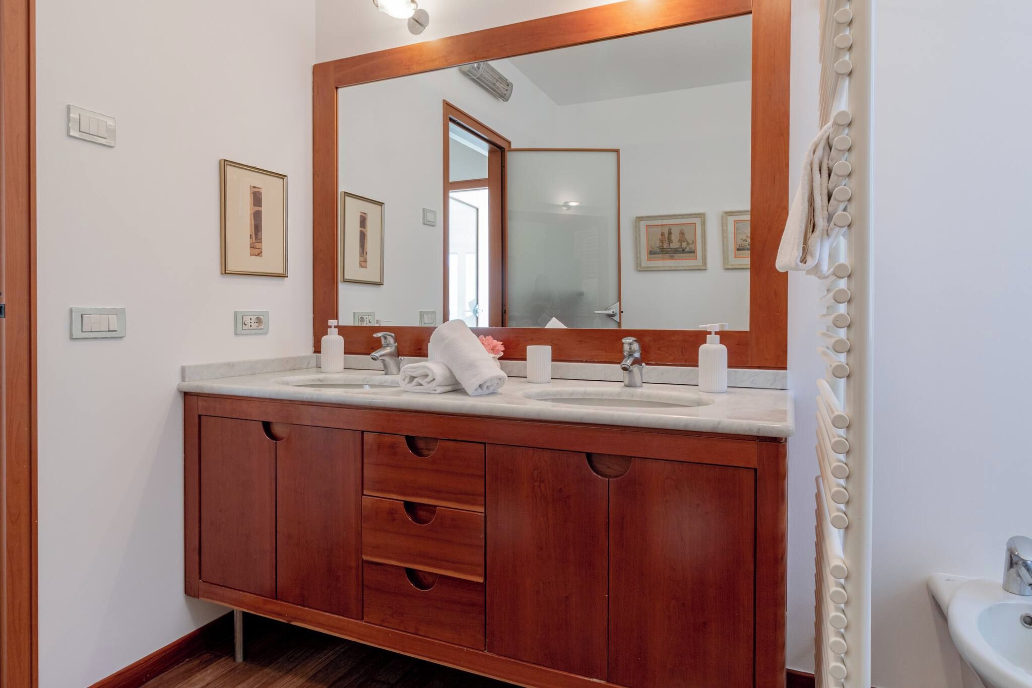 A bathroom with a wooden vanity, a large mirror, and a sink.