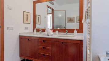 A bathroom with a wooden vanity, a large mirror, and a sink.