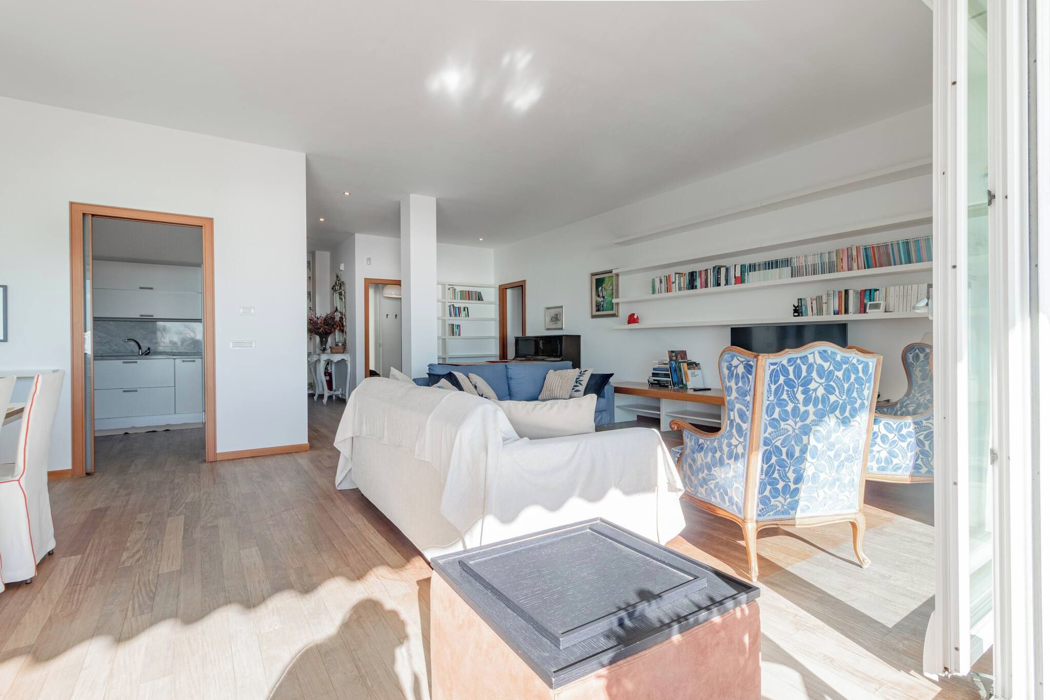 A spacious living area with a sofa, a coffee table, and a bookshelf filled with books.
