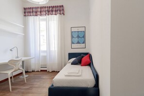 Un dormitorio con una cama, un escritorio y una silla.