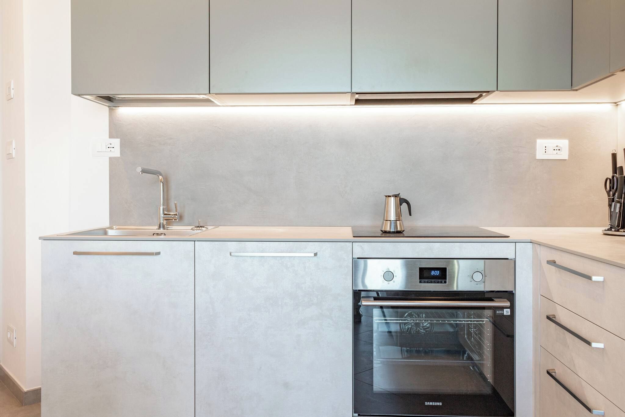 A modern kitchen with stainless steel appliances, including a dishwasher and an oven, and a coffee maker on the counter.