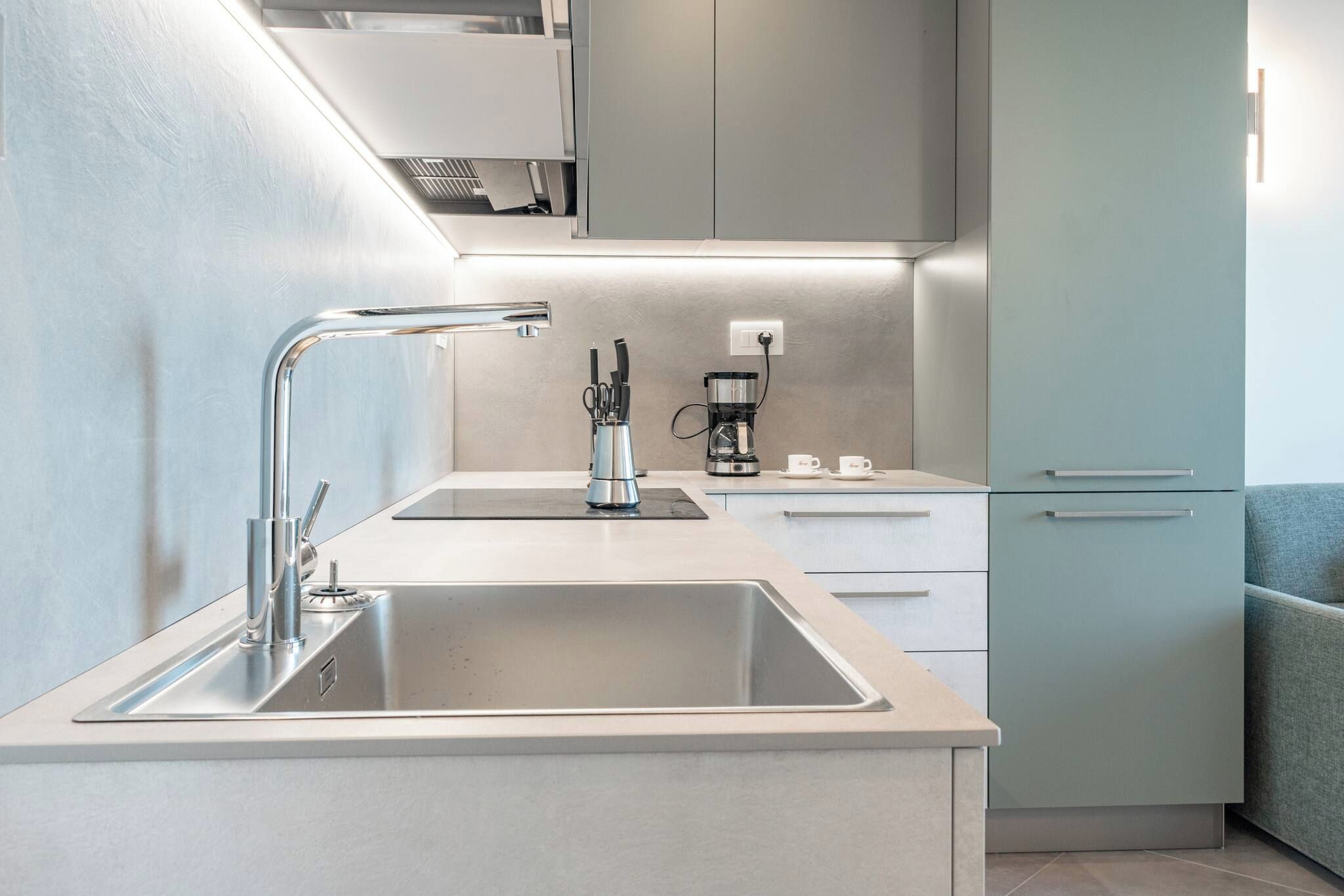 A modern kitchen with a stainless steel sink, a coffee maker, and a built-in oven.