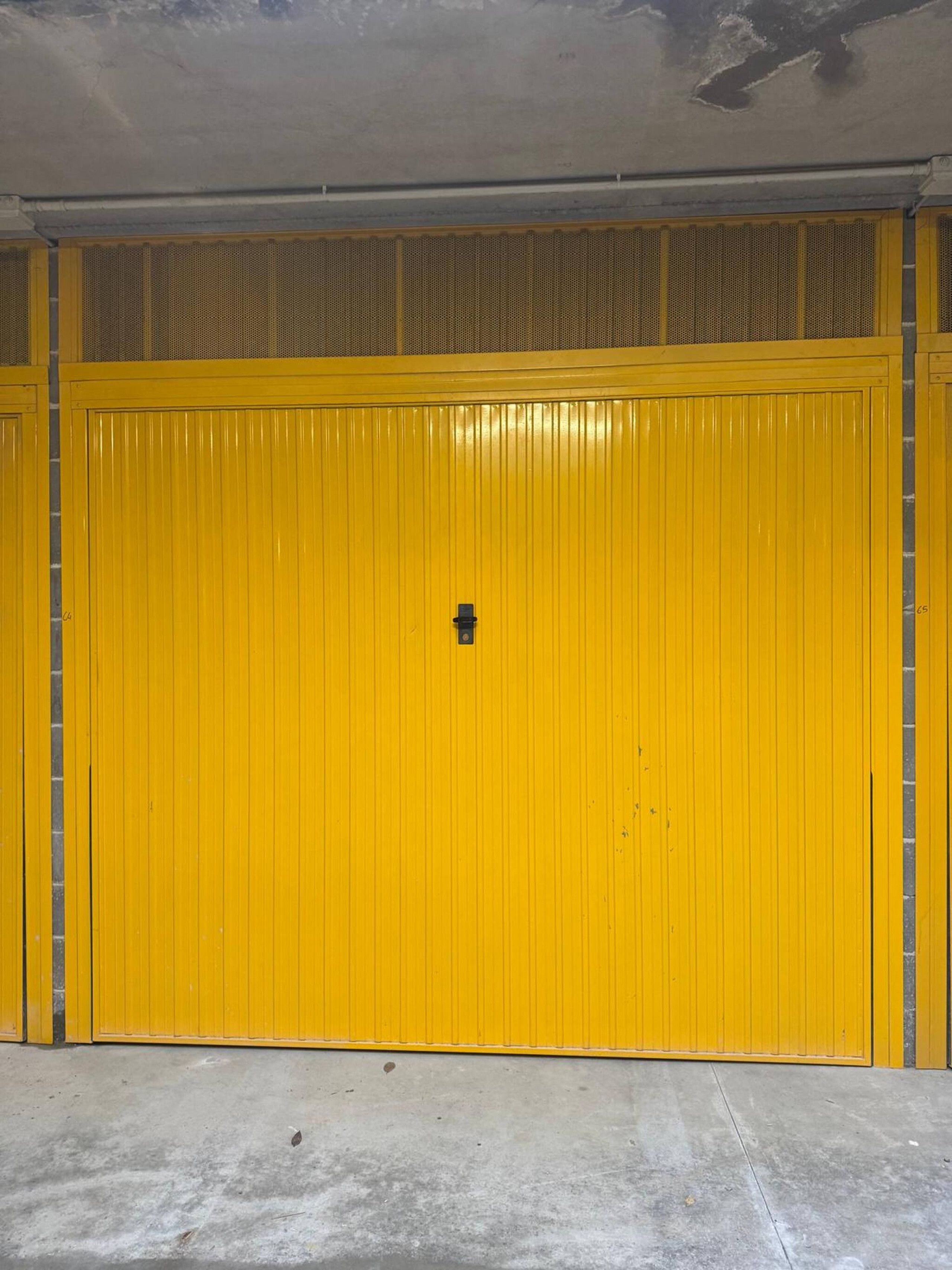 Eine große, gelbe Garagentür mit einer kleinen, schwarzen Schlossvorrichtung in der Mitte.