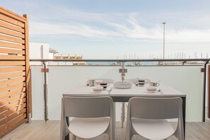 Un balcone con tavolo e sedie, affacciato su una marina piena di barche.