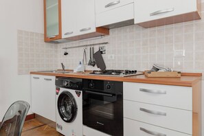 Eine kompakte Küche mit Waschmaschine, Backofen und kleiner Arbeitsfläche.