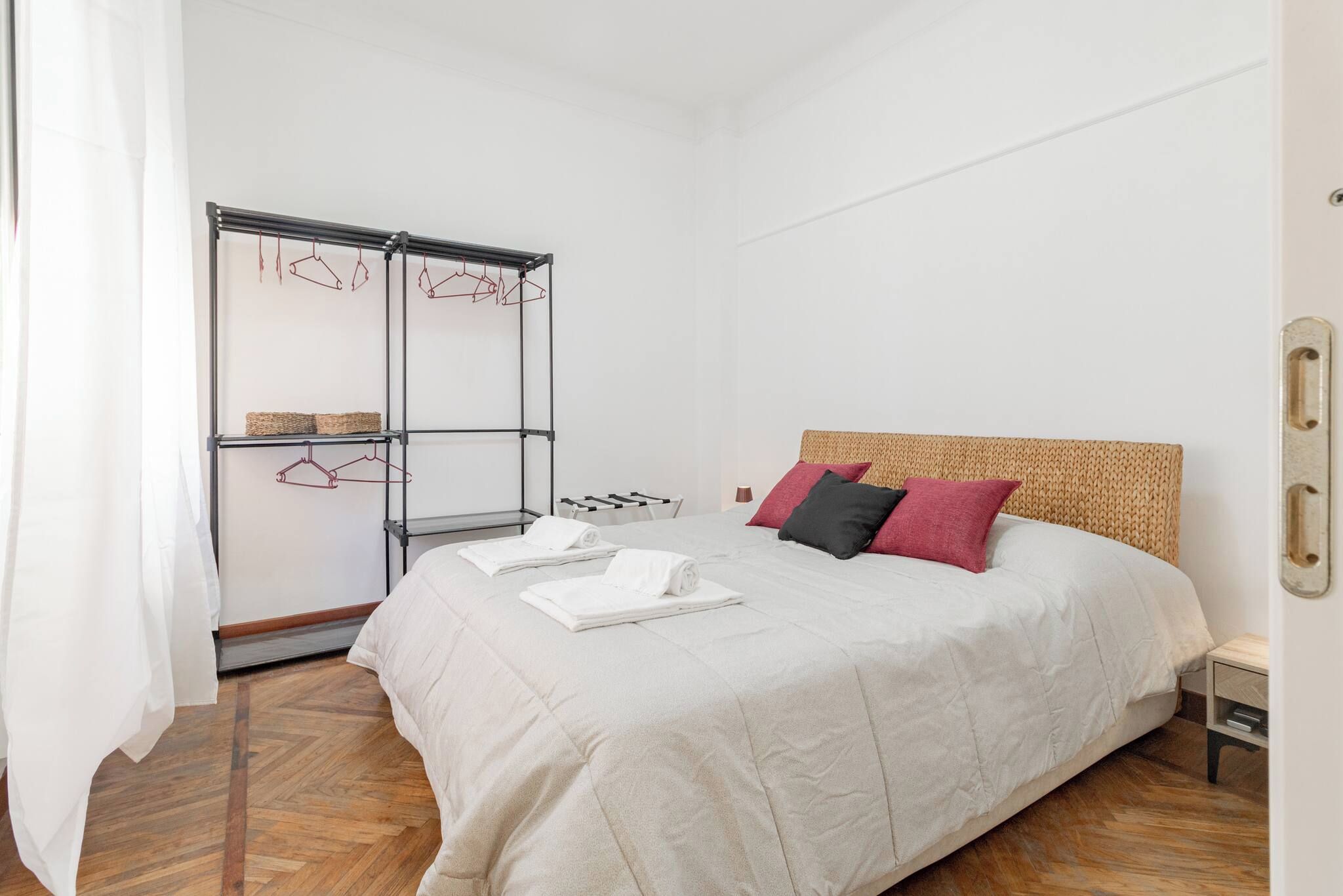 A hotel room with a bed, a wardrobe, and a drying rack.