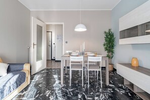 Een moderne kamer met een eethoek, een bed en een plant.