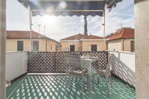 A balcony with a table and chairs, a patterned floor, and a view of neighboring buildings. - DA DADA - Parcheggio (Arma di Taggia)