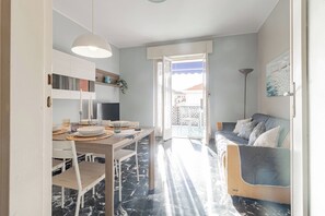 A modern interior with a dining area, a sofa, and a view through an open door. - DA DADA - Parcheggio (Arma di Taggia)