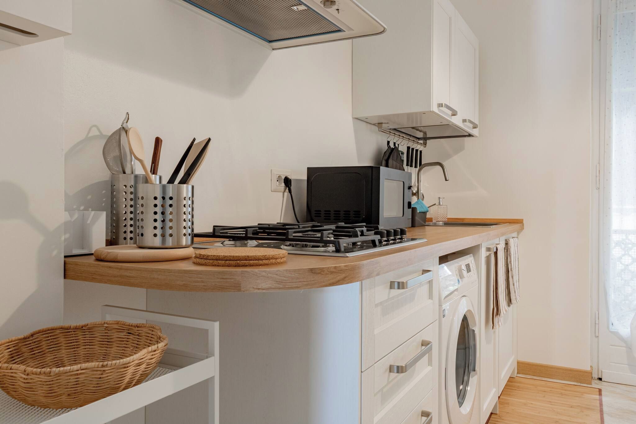 A compact kitchen with a gas stove, microwave, and built-in washing machine.