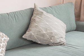 A green sofa with a geometric-patterned pillow. - APPARTAMENTO AZUL - Centro Sanremo (Sanremo)