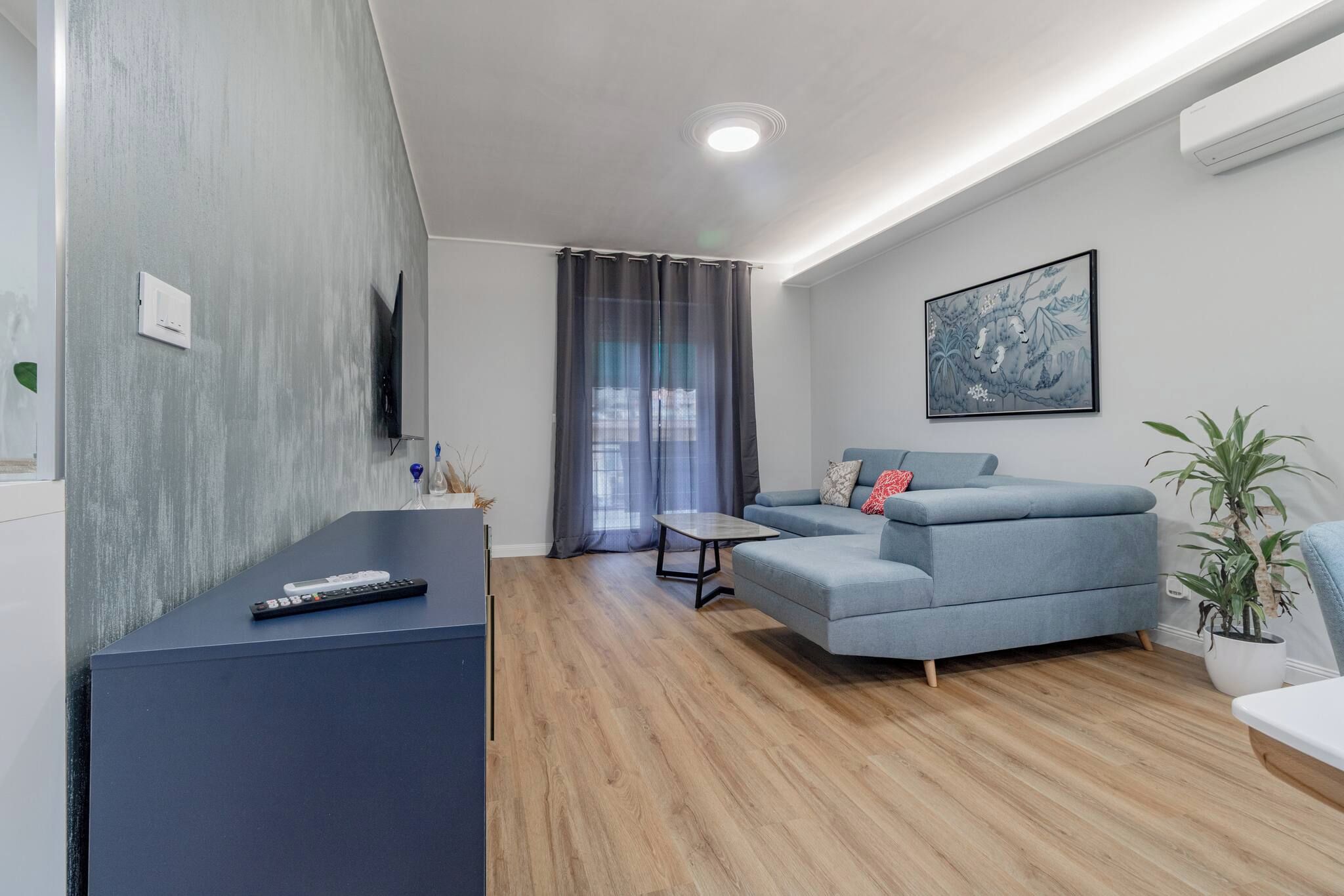 Uma sala de estar moderna com um sofá, uma mesa de centro e uma TV fixada na parede.