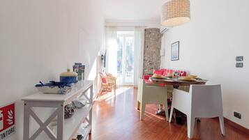 Un salon lumineux avec un coin repas, un mur en pierre et une vue sur l’extérieur.