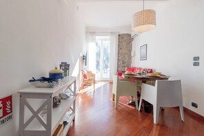 Ein helles Wohnzimmer mit Essbereich, einer Steinwand und Blick ins Freie.