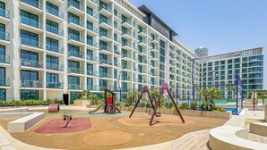 Un hotel moderno con una zona de juegos que incluye columpios y un tobogán.