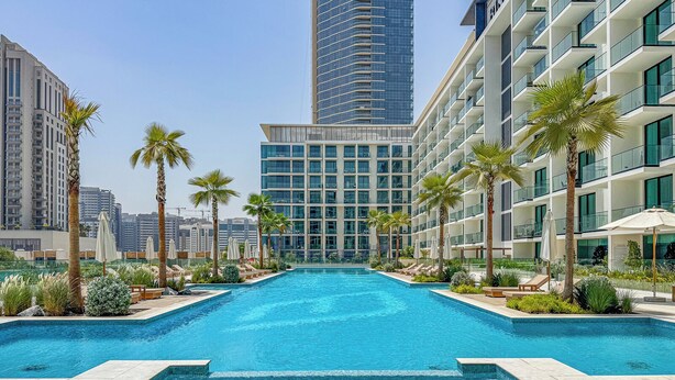 Una piscina con vistas a edificios modernos y palmeras.