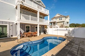 A two-story house with a pool, outdoor furniture, and a white fence. - Luxury Coastal Escape with Private Pool, BBQ Grill & Family Amenities in Corolla, North Carolina (Corolla)
