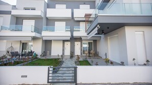 A modern multi-story residential building with balconies, a covered outdoor seating area, and a gated entrance. - GREEN ALMOND D1.2 FAMILY FRIENDLY (Paralia Ofriniou)