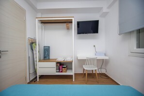 Une chambre à coucher comprenant un lit, un bureau, une chaise, un téléviseur et une armoire.