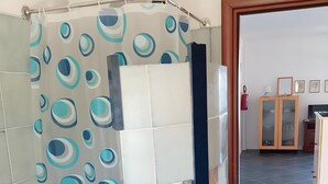 Ein Badezimmer mit Duschvorhang mit Kreismustern, einer gefliesten Wand, einem Waschbecken und einem Schrank mit Glastüren.