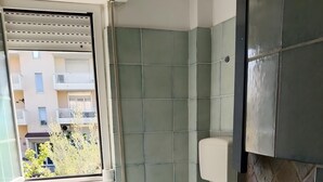A bathroom with a toilet, sink, and window.