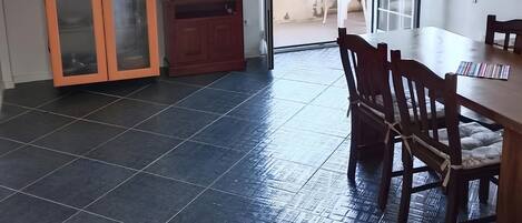 A room with a dining table, chairs, a TV, a cabinet, and a sliding glass door leading to an outdoor area.