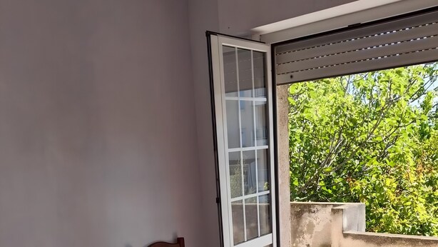 A room with a bed, a chair, and a sliding glass door leading to an outdoor area.