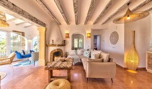 A spacious living area with a fireplace, a sofa, a dining table, and a large window. - Villa Granadella with Sea Views in Jávea, Pool & BBQ for Weekly Retreats and Families (Costa Nova)