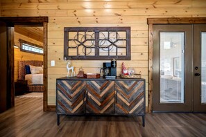 A wooden interior with a chevron-patterned cabinet, a decorative wall piece, and a bed in the background. - Cozy Cabin with Hot Tub & Fireplace in Broken Bow, Oklahoma (Broken Bow)