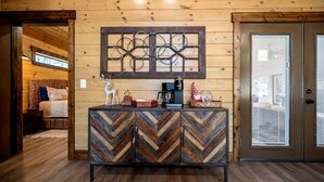 A wooden interior with a chevron-patterned cabinet, a decorative wall piece, and a bed in the background. - Cozy Cabin with Hot Tub & Fireplace in Broken Bow, Oklahoma (Broken Bow)