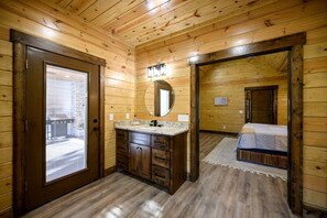 Ein Holzblockhaus-Interieur mit Bad, einem Bett und einer Tür zu einem Außenbereich.