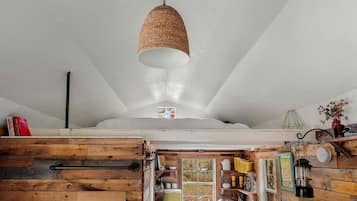A rustic kitchen with wooden cabinets, a hanging light fixture, and a window with a view of the outdoors.