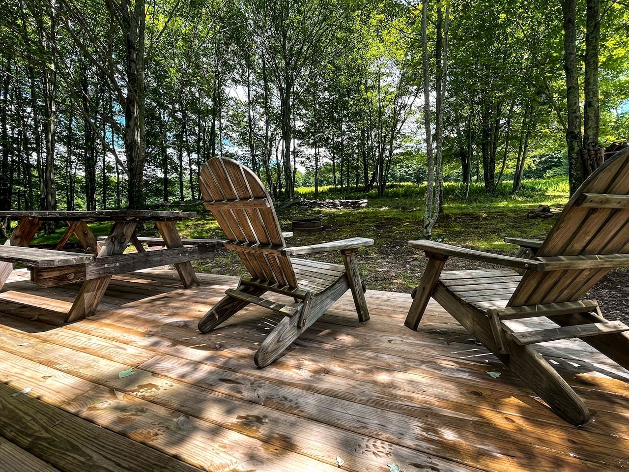 Una terraza con sillas Adirondack de madera y una mesa de picnic.