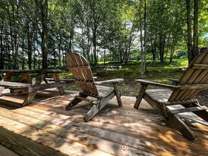 Una terraza con sillas Adirondack de madera y una mesa de picnic.
