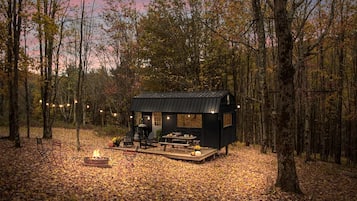 Une cabane dotée d’une terrasse, d’un foyer extérieur et de meubles de jardin.
