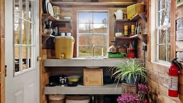 Une cuisine de taille réduite avec des murs en bois, une fenêtre et divers ustensiles de cuisine.